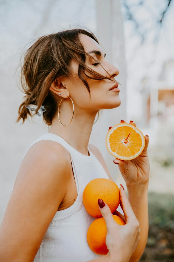 Happy person with oranges outside, embracing a healthy routine.